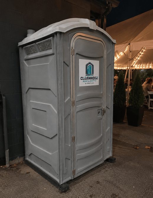 Cleanridge portable toilet placed beside a lit event tent in the evening